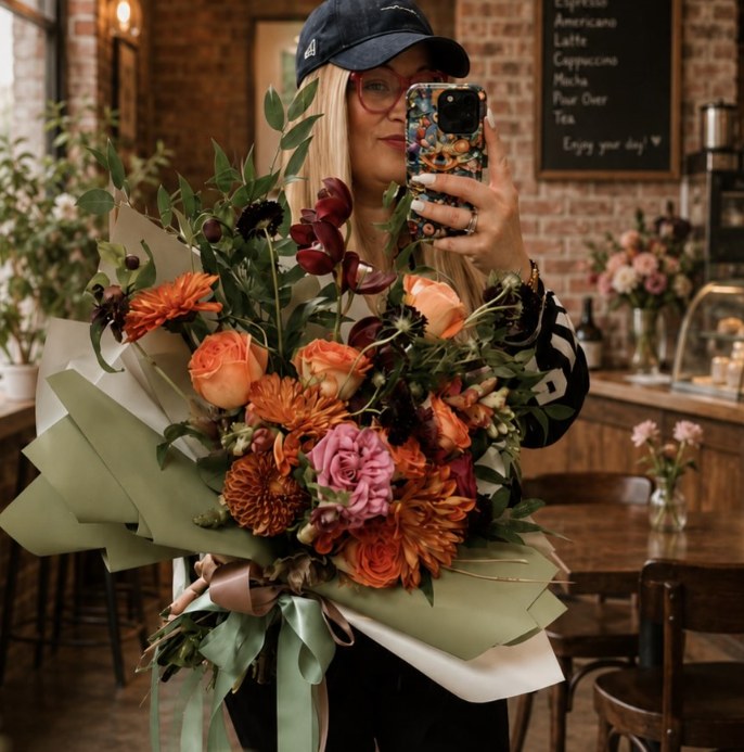 Large autumn bouquet of orange roses, dahlias and orchids wrapped in olive paper