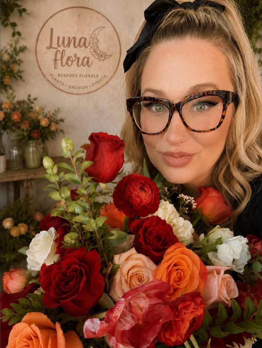 Chentea, floral designer at Luna Fiora, holding a red and orange rose arrangement