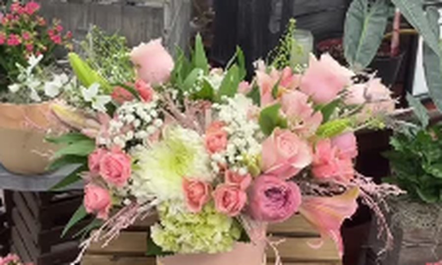 Soft pastel garden-style arrangement of roses, hydrangea, and lisianthus in a blush bowl